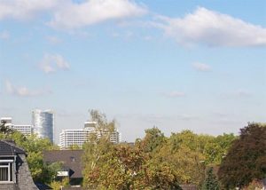 Stadtsilhouette mit bewölktem Himmel und Bäumen.
