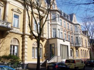 Historische Gebäude mit Bäumen und geparkten Autos