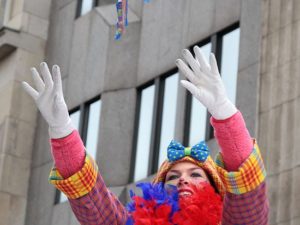 Kostümierter Clown wirft Konfetti in die Luft.