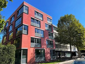Modernes rotes Gebäude mit Bäumen davor.